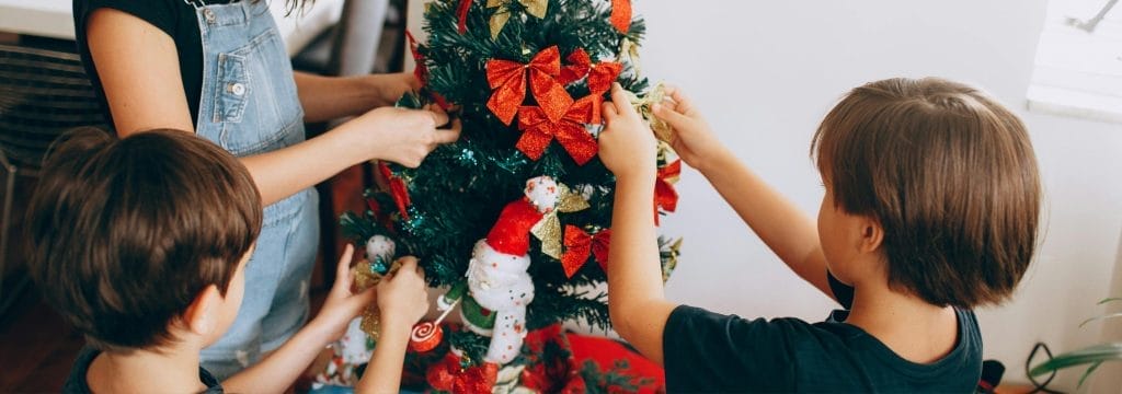 Children decorating a Christmas tree together, reflecting how to talk to children at Christmas about grief and remembrance.