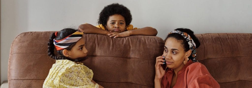 A parent and children sitting together on a sofa, showing how to talk to children at Christmas about grief through open conversation.